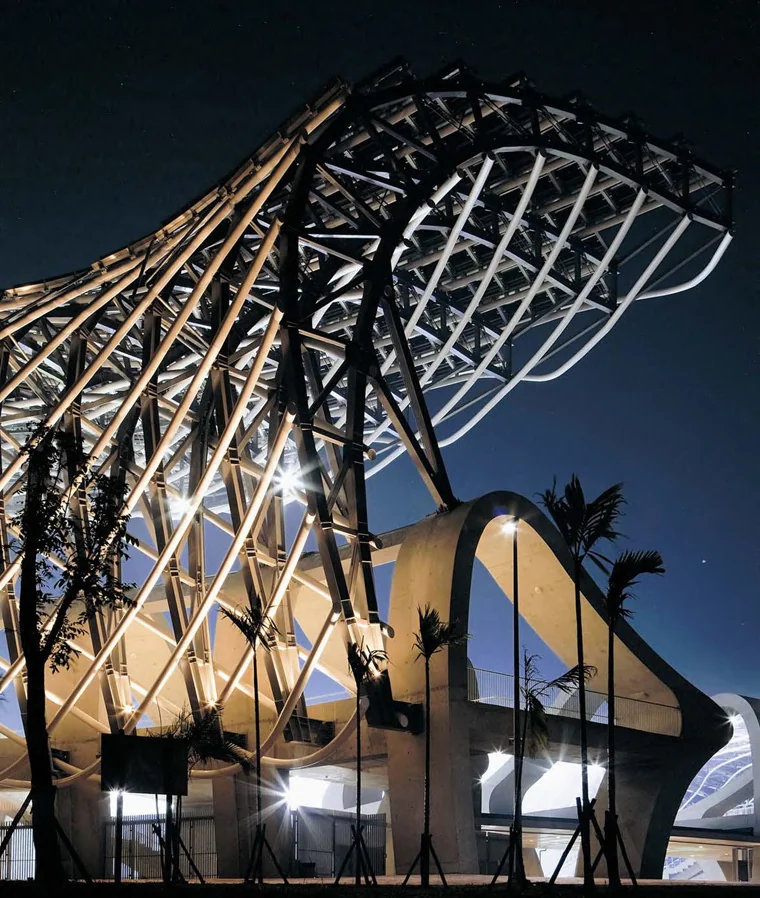 The stadium's steel lattice roof lit at night.
